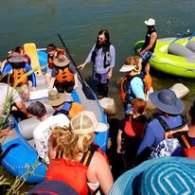 Group of people with rafts and life jackets preparing for a river activity.